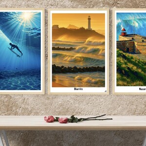 Peut inclure: Trois impressions d'art encadrées représentant des scènes océaniques. L'une montre un surfeur sous l'eau, une autre un phare au coucher du soleil et la troisième un fort côtier avec une grande vague. Les impressions sont exposées au-dessus d'une table en bois.