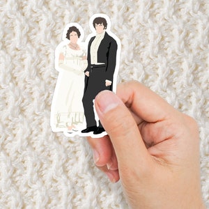 May include: A sticker featuring a couple in formal attire. The woman is wearing a white dress with a white shawl and the man is wearing a black suit with a white shirt and a black bow tie.