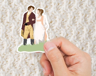 May include: A sticker featuring a cartoon illustration of a couple in period clothing. The man is wearing a brown jacket, yellow pants, and black shoes. The woman is wearing a white dress. They are standing in a green field.