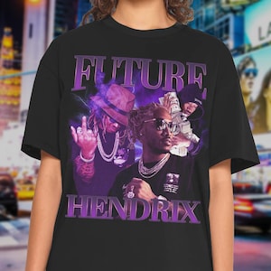 May include: Black t-shirt featuring a purple graphic of the words "FUTURE" and "HENDRIX" with a portrait of a man wearing sunglasses and jewelry. The design has a vintage, retro style.