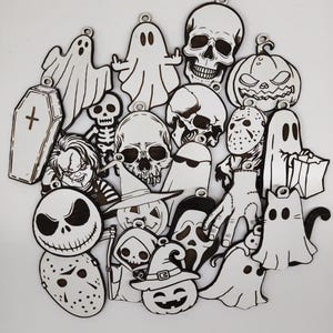 Puede incluir: Una colección de recortes de madera con temática de Halloween en blanco y negro. El surtido incluye fantasmas, calaveras, calabazas, un ataúd y personajes como Chucky y Jack Skellington. Cada recorte tiene un pequeño agujero para colgar.