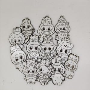 May include: A selection of wooden bunny charms, each with a unique outfit and expression. The charms are outlined in black and have a small hole for hanging. Designs include hats, bows, and other accessories, all in a cartoon style.