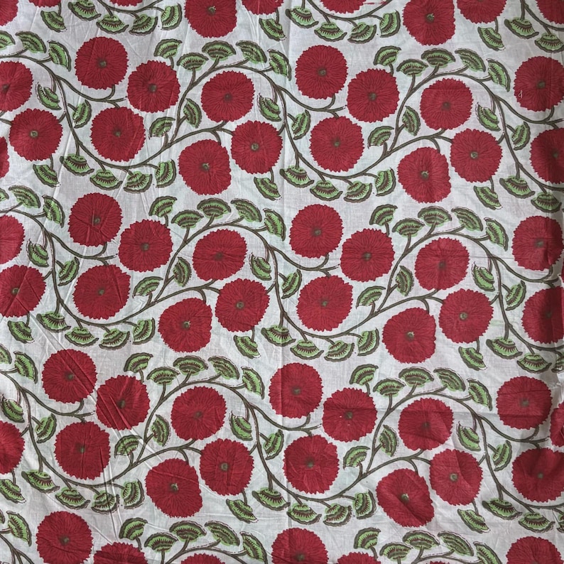 May include: A white fabric featuring a repeating pattern of dark red circular flowers with textured centers. The flowers are connected by winding brown stems adorned with small, light green leaves arranged in a continuous, flowing vine design.