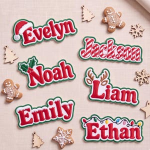 May include: Six custom name ornaments featuring red lettering with green borders. Names include Evelyn with a Santa hat, Jackson with candy cane stripes, Noah with holly, Liam with reindeer antlers, Emily with snow, and Ethan with Christmas lights.