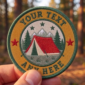 May include: A circular embroidered patch featuring a red tent, green pine trees, and white mountain peaks. The border is dark green with a mustard yellow background. The text "YOUR TEXT" and "ANY HERE" is stitched in dark green lettering.
