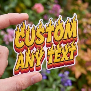 May include: An embroidered patch featuring the text CUSTOM ANY TEXT in a bold, yellow font with a flame-like design at the top and bottom. The lettering has a layered gradient effect transitioning from yellow to orange, red, and dark red.