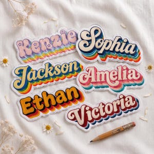 May include: Six custom name patches featuring retro-style typography with layered rainbow-colored outlines. The names Kenzie, Sophia, Jackson, Amelia, Ethan, and Victoria are displayed in various colors, including pink, blue, yellow, and red, with a pencil.