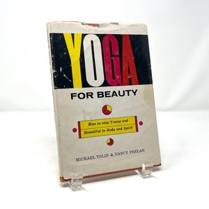 May include: A vintage book titled "Yoga for Beauty: How to stay Young and Beautiful in Body and Spirit" by Michael Volin & Nancy Phelan. The cover features a colourful graphic design with the word "Yoga" in large, bold letters.