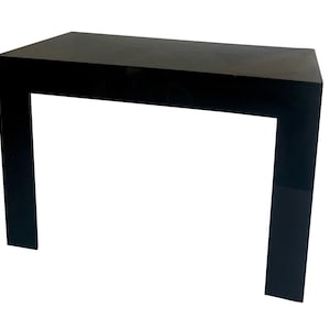 May include: A modern, black side table with a rectangular top and a U-shaped base. The table is made of a solid, dark material and has a minimalist design. The table is approximately 30 inches long, 15 inches wide, and 28 inches high.