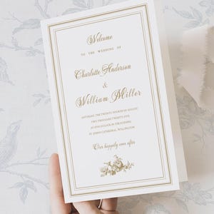 May include: A wedding invitation with gold lettering and a double gold border. The invitation reads "Welcome to the Wedding of Charlotte Anderson & William Miller" and includes the date, time, and location. A floral design is at the bottom.