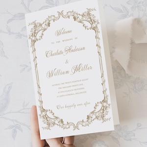 May include: A white wedding program with gold lettering and a decorative border. The text reads "Welcome to the Wedding of Charlotte Anderson & William Miller." The date and time of the wedding are also included. The program is held by a hand.
