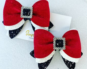 May include: Two red, white, and black layered bows with a silver buckle embellished with rhinestones. The bows are handmade and have a glittery finish.