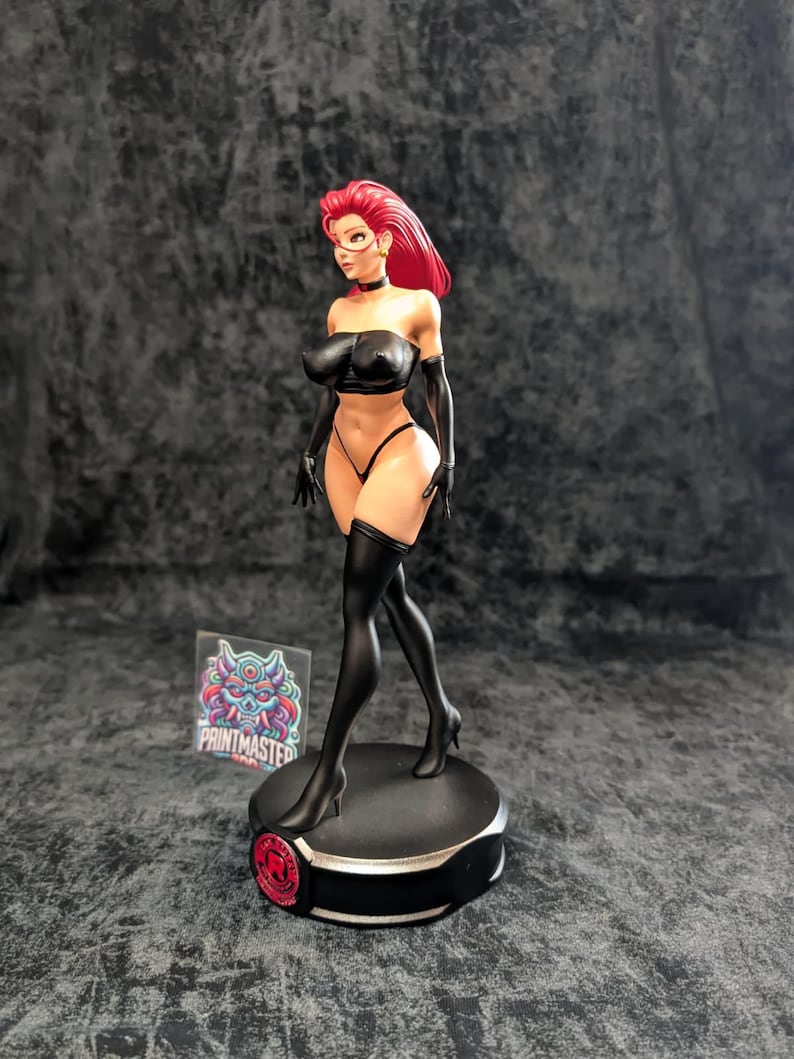 May include: A detailed figurine of a woman with red hair, wearing a black outfit, including a top, underwear, gloves, and thigh-high stockings. The figure is standing on a black base with a red accent. The Printmaster logo is visible.