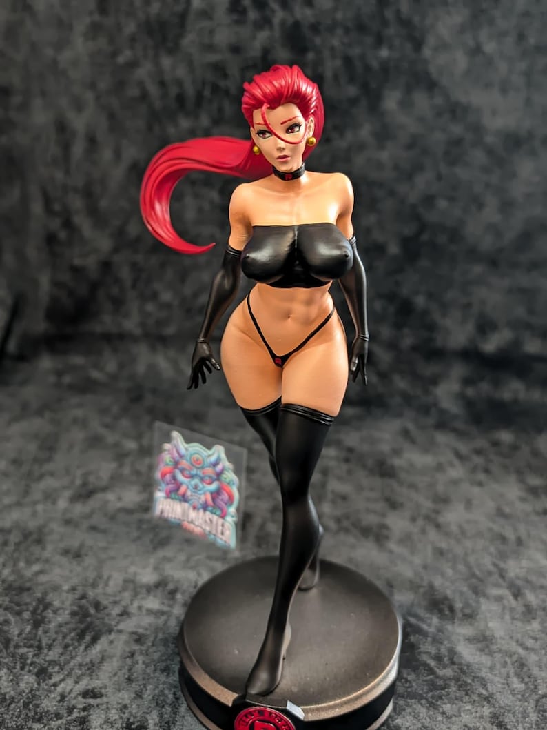 May include: A detailed figurine of a woman with red hair, wearing a black top, gloves, and thigh-high stockings. The figure is posed on a round base, with a small logo visible near the base. The figurine has a detailed design.