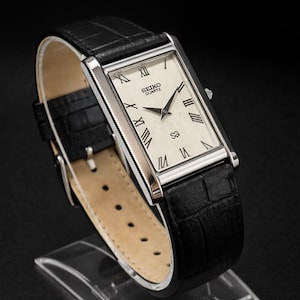 Reloj Seiko Tank vintage: esfera delgada con números romanos, correa de cuero negro.