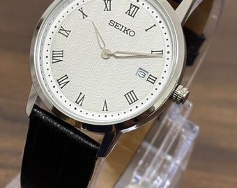 Vintage Seiko herrklocka med smal kvartsur, läderarmband, vit urtavla och datumindikator