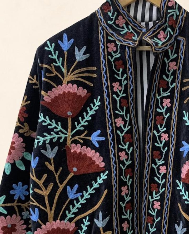 May include: A dark navy blue embroidered jacket with a floral design. The jacket features a collar and is adorned with colorful embroidered flowers in shades of red, pink, blue, and green. The interior lining has a striped pattern.