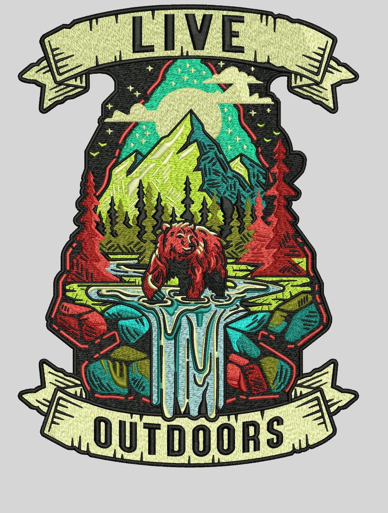 May include: Embroidered patch with a nature scene. A brown bear stands in a stream in front of a mountain range, trees, and a waterfall. The patch has the words "LIVE" and "OUTDOORS" in a banner.