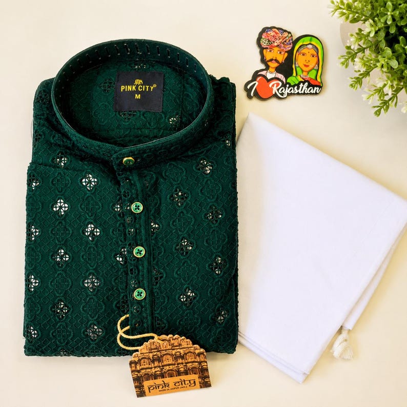 K&ouml;nnte beinhalten: Ein dunkelgr&uuml;ner Langarm-Kurta mit einem komplizierten Stickmuster mit kleinen Spiegelakzenten, einem Stehkragen und einer Knopfleiste. Enth&auml;lt ein schlichtes wei&szlig;es Stoffst&uuml;ck und ein Etikett mit dem Text Pink City.