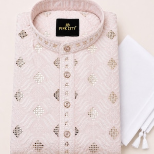 May include: A light pink kurta featuring a mandarin collar, a button-down placket, and intricate white embroidery with reflective mirror accents in a diamond pattern. A black label with the text PINK CITY is inside the collar. A white cloth is adjacent.