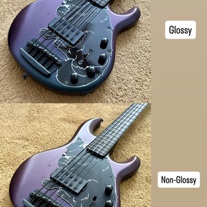 Op de afbeelding: Een paarse basgitaar met een zwarte slagplaat en zilveren hardware. De bas heeft een uniek ontwerp met witte accenten en de teksten "Glossy" en "Non-Glossy". Het instrument heeft zes snaren en staat tegen een neutrale achtergrond.