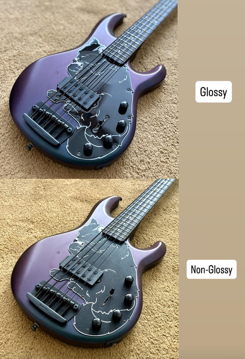 Op de afbeelding: Een paarse basgitaar met een zwarte slagplaat en zilveren hardware. De bas heeft een uniek ontwerp met witte accenten en de teksten "Glossy" en "Non-Glossy". Het instrument heeft zes snaren en staat tegen een neutrale achtergrond.