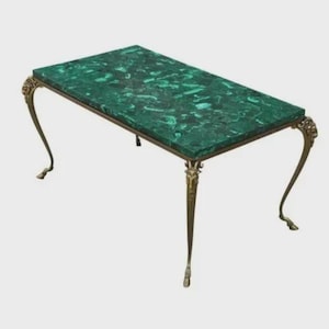 May include: A rectangular coffee table with a malachite top and ornate brass legs. The table's top is a vibrant green with a marbled pattern. The legs are curved and feature decorative details.