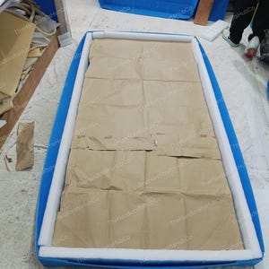 以下が含まれることがあります： 白いフォームパッドと茶色の紙が入った長方形の青い容器。容器には「The HandicraftsHubCo」の文字が印刷されています。容器は開いており、梱包の準備ができています。