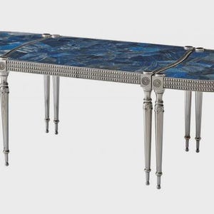 May include: An oval-shaped, silver-toned table with a mosaic blue tabletop. The table has multiple slender legs and decorative detailing around the edges. The tabletop is made of blue stone pieces.