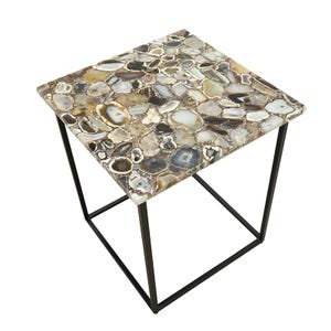 May include: A square side table featuring a tabletop composed of numerous polished, multi-colored agate slices in shades of brown, gray, white, and tan. The tabletop is supported by a simple, thin, black metal frame with four straight legs.