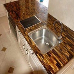 May include: A kitchen island with a stainless steel sink, a black cooktop, and white cabinets. The countertop is made of a brown and gold material with a striped pattern. The faucet is chrome.