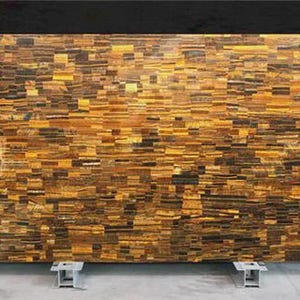 May include: Large rectangular slab with a mosaic pattern of rectangular pieces in shades of gold, brown, and black. The slab is supported by two metal stands. The overall effect is a textured, natural stone appearance.