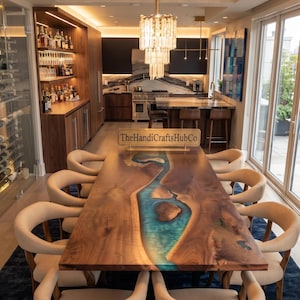 May include: A rectangular dining table featuring a natural wood grain surface with a central river-like inlay of translucent blue resin. A gold-toned sign with the text TheHandiCraftsHubCo sits on the table, surrounded by ten beige chairs.