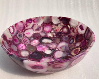 May include: Oval-shaped decorative bowl crafted from polished agate stones. The bowl features a mosaic of pink, purple, white, and gray stones, creating a unique and colorful pattern. The bowl is a decorative item.