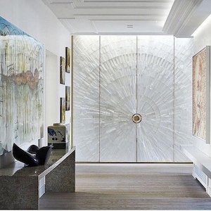 May include: A contemporary hallway featuring a large cabinet with a radial design. The cabinet doors are white with a sunburst pattern. Artwork and a console table with a sculpture are also visible. The floor is wooden.