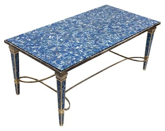 May include: Rectangular coffee table with a blue and white patterned top. The table has gold-colored metal accents and four tapered legs. The legs are dark blue with gold detailing. The table is approximately 48 inches long.
