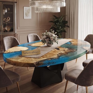 May include: An oval dining table featuring a natural wood slab with live edges and a vibrant blue resin inlay. The table is supported by a black geometric base and includes a light-colored table runner, a floral centerpiece, and the text TheHandiCraftsHubCo.