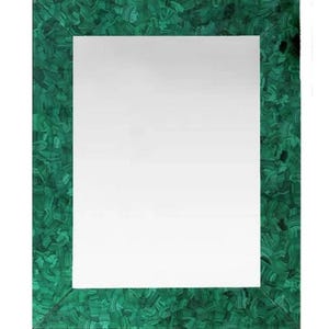 May include: Rectangular mirror with a vibrant green malachite frame. The frame's surface has a swirling pattern of dark and light green hues. The mirror's reflective surface is a bright white.