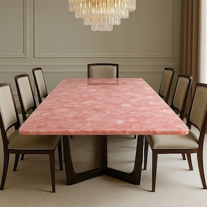 May include: A large rectangular dining table with a pink quartz surface and a dark brown wooden base. Eight wooden chairs with beige upholstery surround the table. A crystal chandelier hangs above the table, adding a touch of elegance.