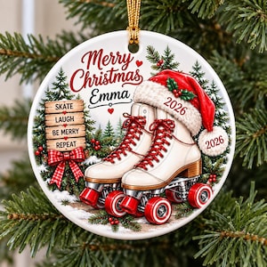 May include: A round white ceramic Christmas ornament featuring a pair of white roller skates with red laces and wheels. The design includes a red Santa hat, a wooden sign with the text SKATE LAUGH BE MERRY REPEAT, and the name Emma with 2026.
