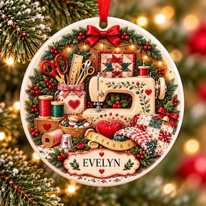 May include: A round ceramic Christmas ornament featuring a sewing theme with a vintage sewing machine, red scissors, spools of thread, a heart-shaped pincushion, a measuring tape, and a quilt. The name EVELYN is printed on a decorative label.