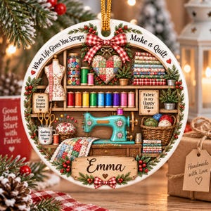 May include: A round ceramic ornament featuring a sewing room scene with a teal sewing machine, colorful thread spools, a mannequin, and a quilt. The text reads When Life Gives You Scraps Make a Quilt, Fabric is my Happy Place, and Emma.