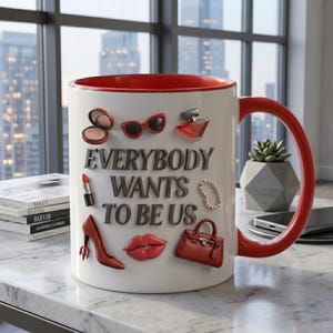 May include: White ceramic mug with a red interior and handle, adorned with red accessories and the phrase "EVERYBODY WANTS TO BE US." Includes lipstick, sunglasses, and a handbag.