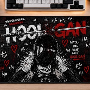 May include: Black and white mousepad with a graphic of a person in a motorcycle helmet. The word "HOOLIGAN" is in white and red, with "HA" and other phrases scattered around. A sword is through the helmet.
