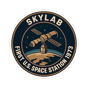 Puede incluir: Una pegatina redonda con el diseño de la estación espacial Skylab. El texto "Skylab" está en la parte superior, con "First U.S. Space Station 1973" en la parte inferior. La imagen central muestra la estación espacial sobre una Tierra estilizada.