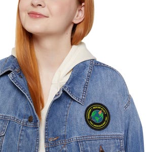May include: A blue denim jacket with a circular patch featuring the text "Friendship 7 - Mercury-Atlas 6" and "First American in Orbit 1962." The patch depicts a globe with a rocket.