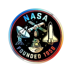May include: A round sticker with the NASA logo, featuring a satellite, space shuttle, and lunar lander on a black background. The text "NASA" is at the top, and "FOUNDED 1958" is at the bottom, with a colorful border.