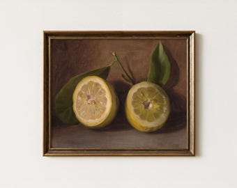 May include: A framed still life painting featuring two halved lemons with green leaves and stems. The lemons are yellow with a light-colored interior, set against a brown background. The frame is a warm gold color.