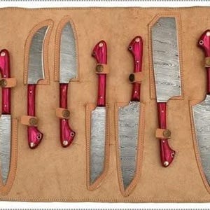 Puede incluir: Un juego de ocho cuchillos de cocina con hojas de acero estampadas y mangos de color rojo brillante. Los cuchillos se muestran en un rollo de cuero marrón con ranuras individuales para cada cuchillo. Los mangos tienen un diseño curvo.