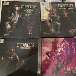 May include: Four boxed board games with the title "Etherfields" are displayed. The boxes feature fantasy art of characters and creatures. The titles on the boxes are "Stretch Goals & Harpy & She-Wolf Campaigns", "Funeral Witch Campaign", "Sphinx Campaign", and "5th Player Expansion".